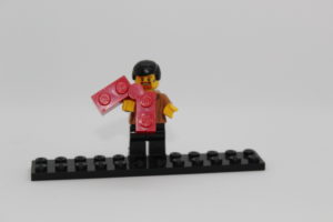 Lego character holding a lego piece with the brand visible.