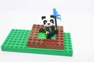 Lego figure with a panda head places a flag to stake a domain.